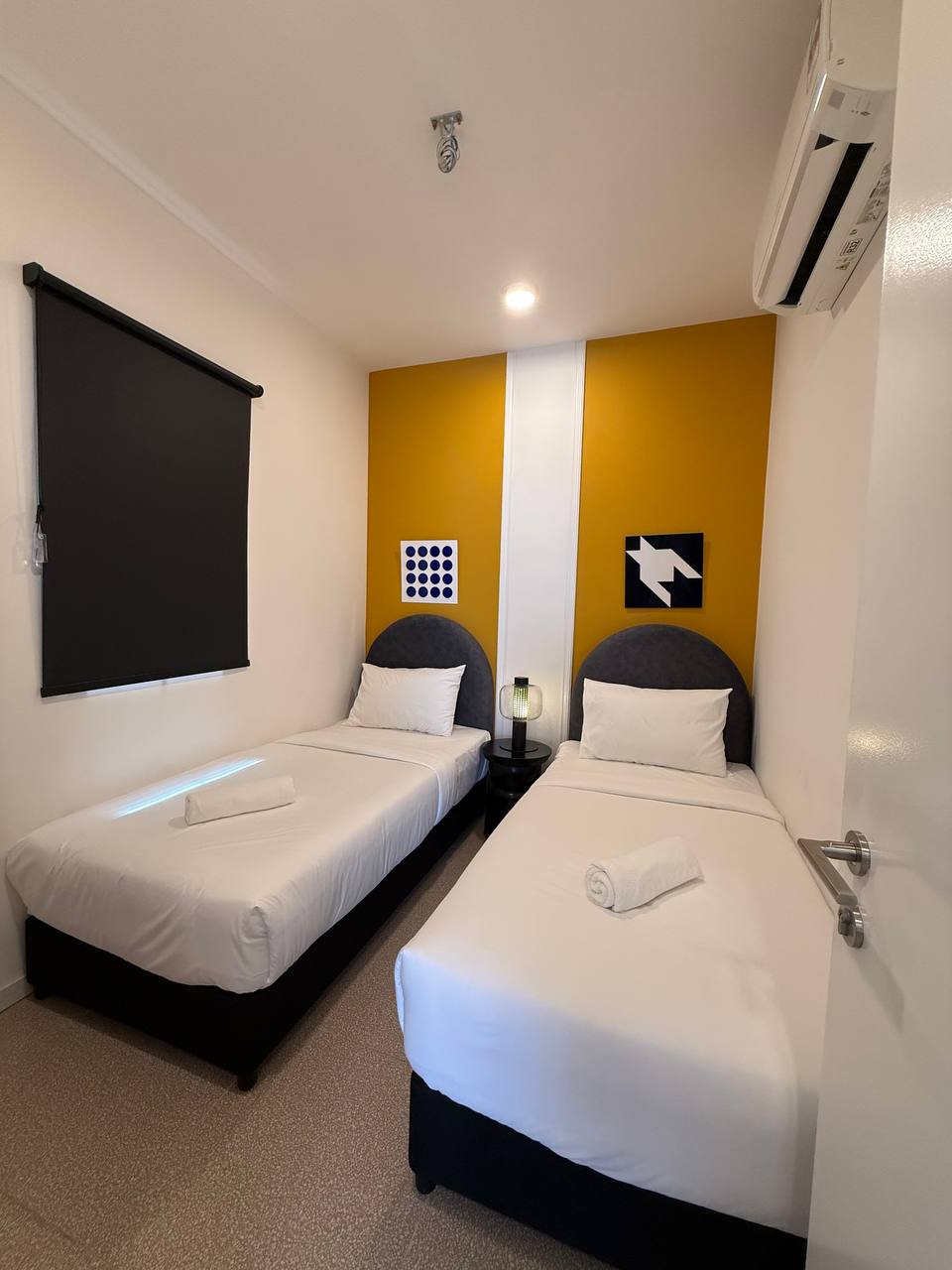 Twin bedroom with two single beds and mustard feature wall