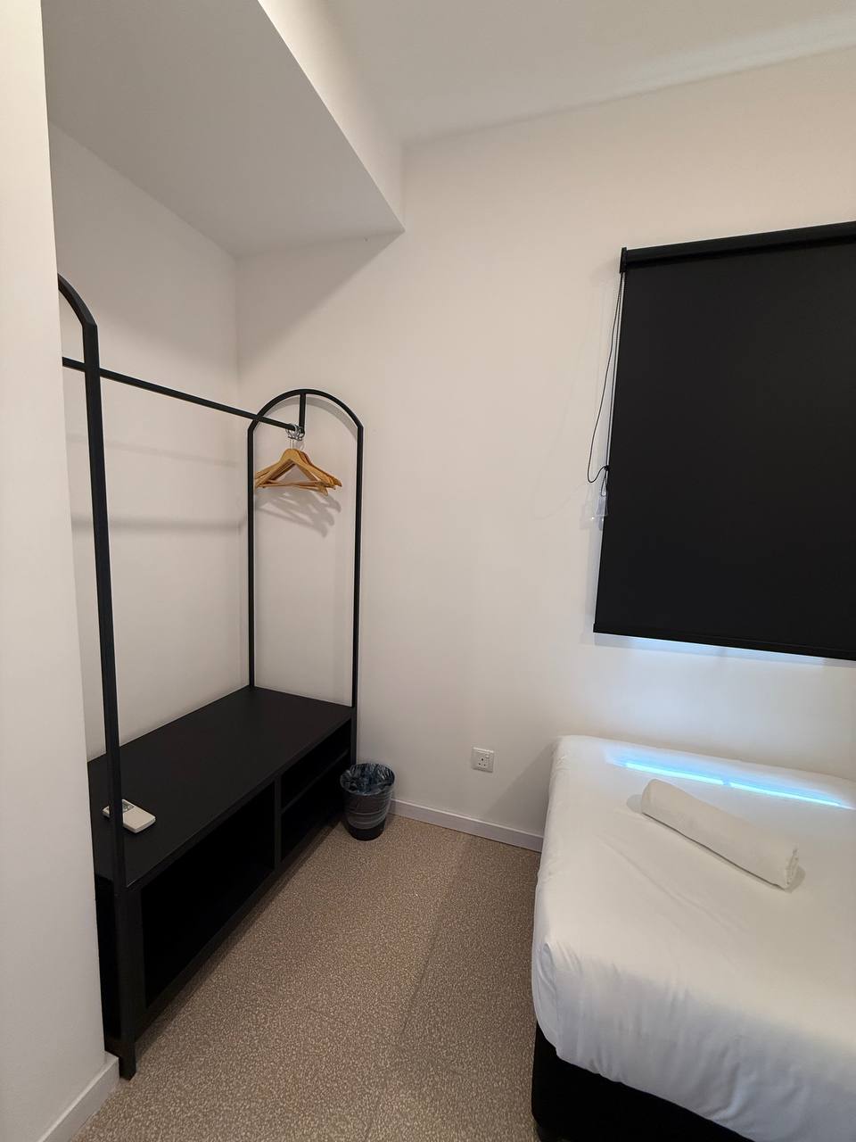 Bedroom with open wardrobe rail, hangers and blackout blind