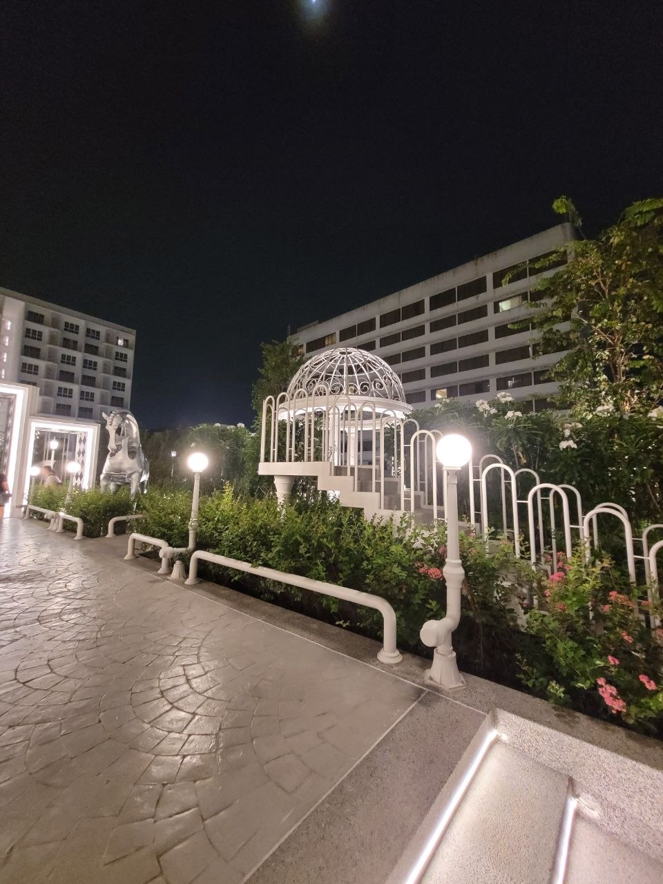 Landscaped garden walkway with white gazebo at night