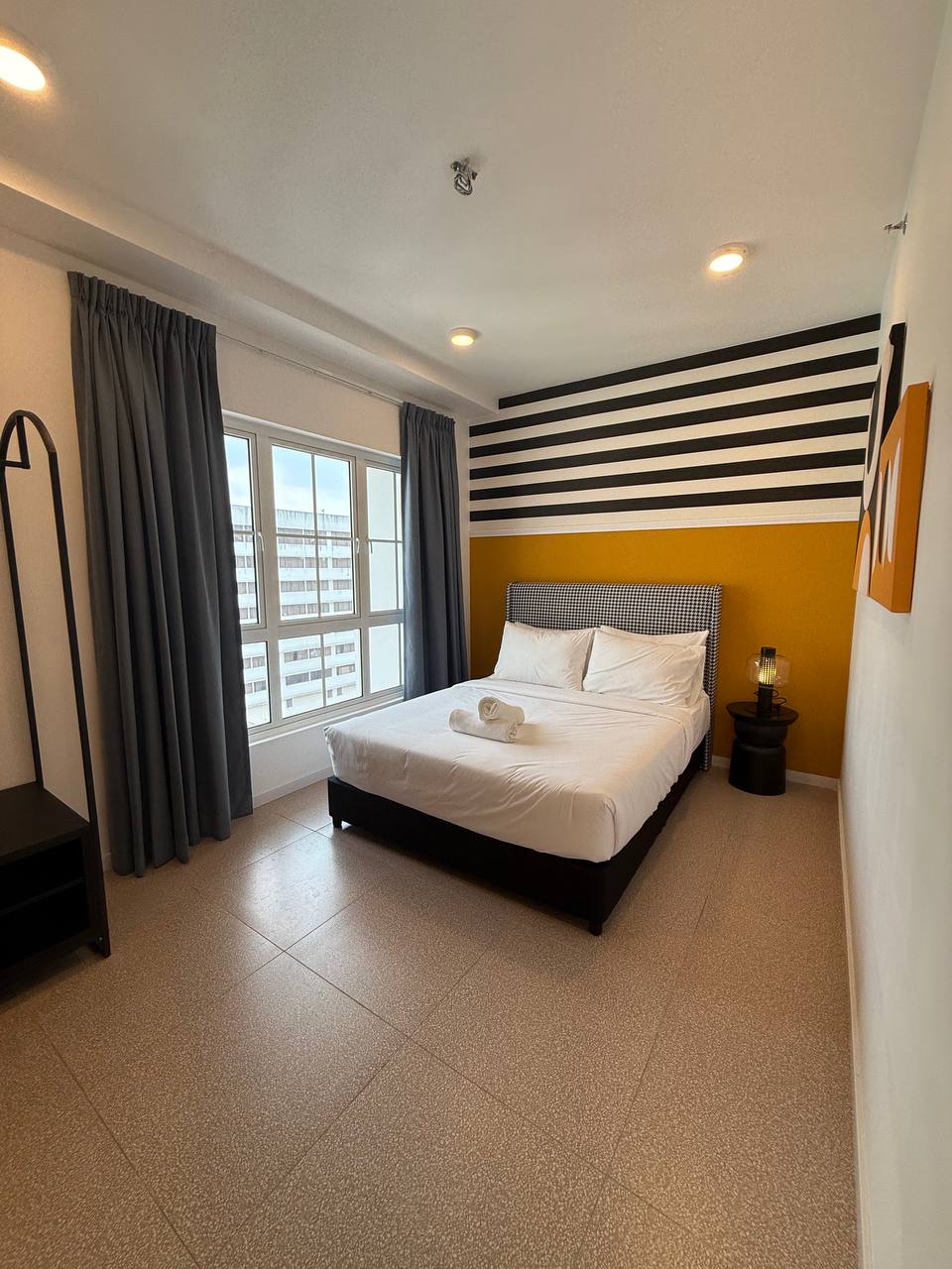 Master bedroom with queen bed, striped feature wall and large window