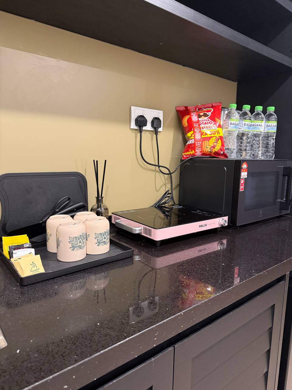 Kitchenette with induction hob, microwave, kettle, mugs and drinking water