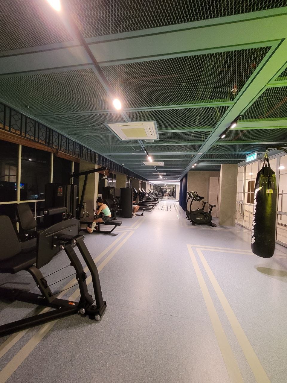 Long gym floor with weight machines, bike and punching bag