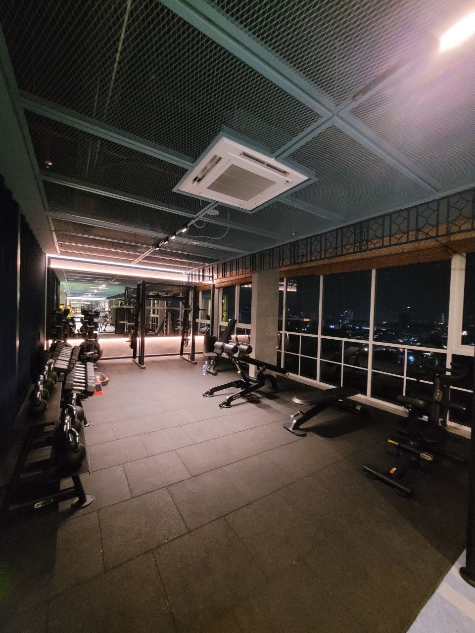 Free weights and benches in the sky gym with night city views